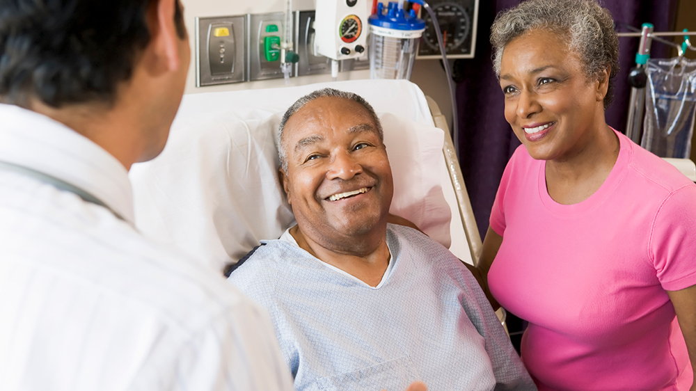 Older smiling couple in hospital talking to doctor
