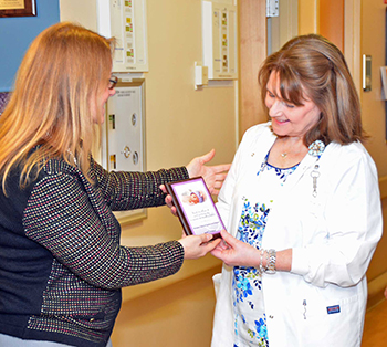 Marie Pokraka (left), director of Program Services, March of Dimes, presents the plaque of gratitude to Cynthia Hawley, RN, director , Holy Cross Hospital NICU