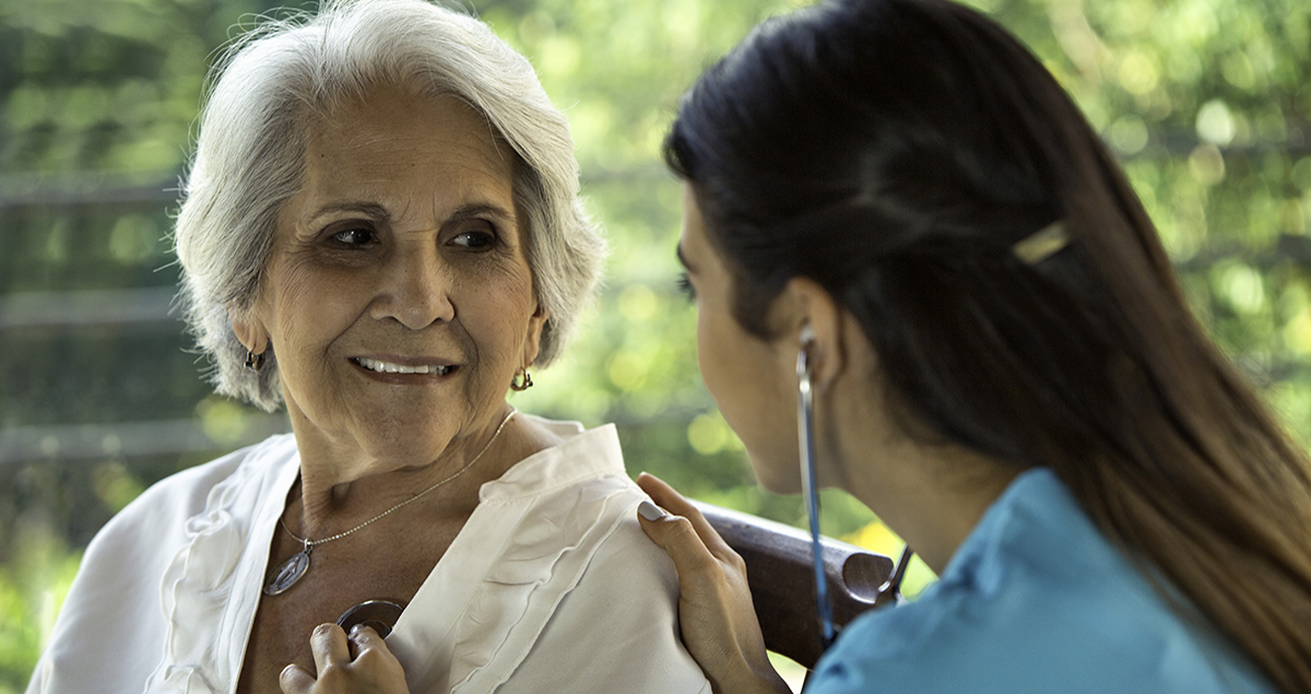 Female physician listens to senior patient's heart